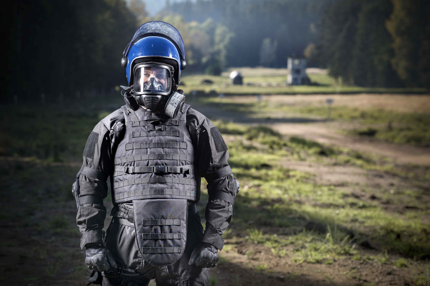 Man wearing riot gear and the MIRA Safety CM-6M riot control gas mask